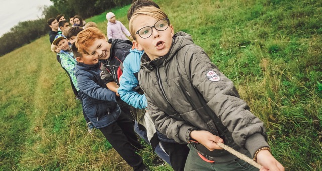 children pulling on a rope on a green field - 1 (1)