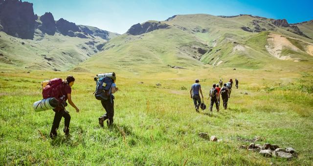 group of people hiking in a green mountain